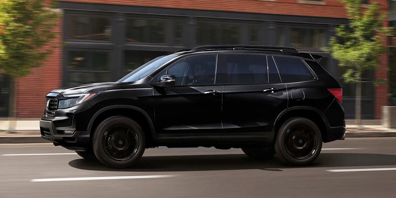 A black 2024 Honda Passport driving down a city street