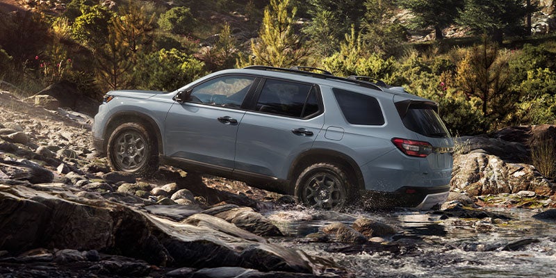 A grey 2025 Honda Pilot driving up a rocky hill